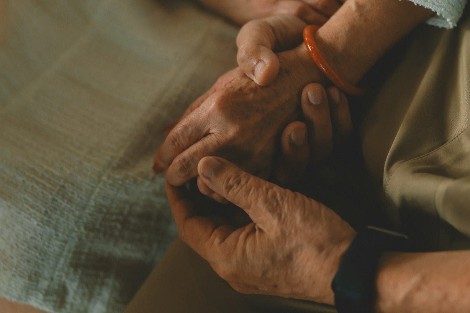 Two hands gently holding one another in warm light