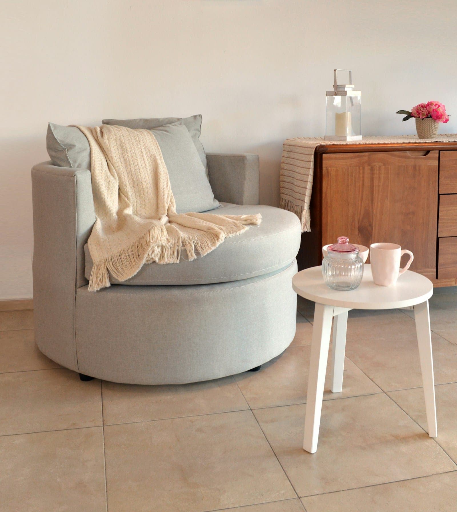 A soft armchair with a folded throw beside a small table